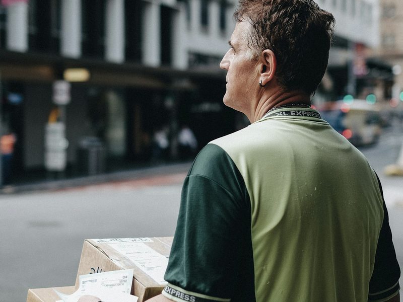 A delivery worker carrying packages through a city street
